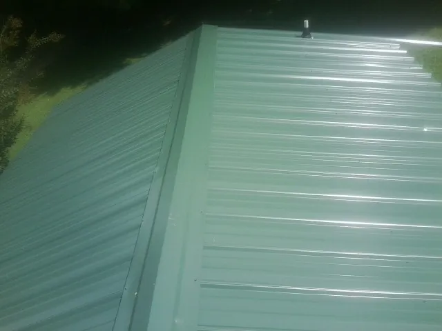 New green metal panels meeting at the ridge of a roof — Flat Roof Repair work by our crew in Talmage