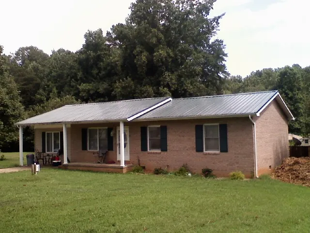 Gray metal roof on a brick ranch house with a side carport in Talmage