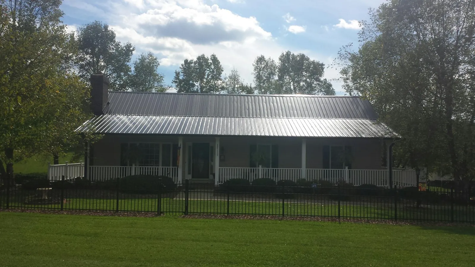 Gray metal roof on a brick ranch with a full width front porch — Gutter Guard Installation work by our crew in Talmage