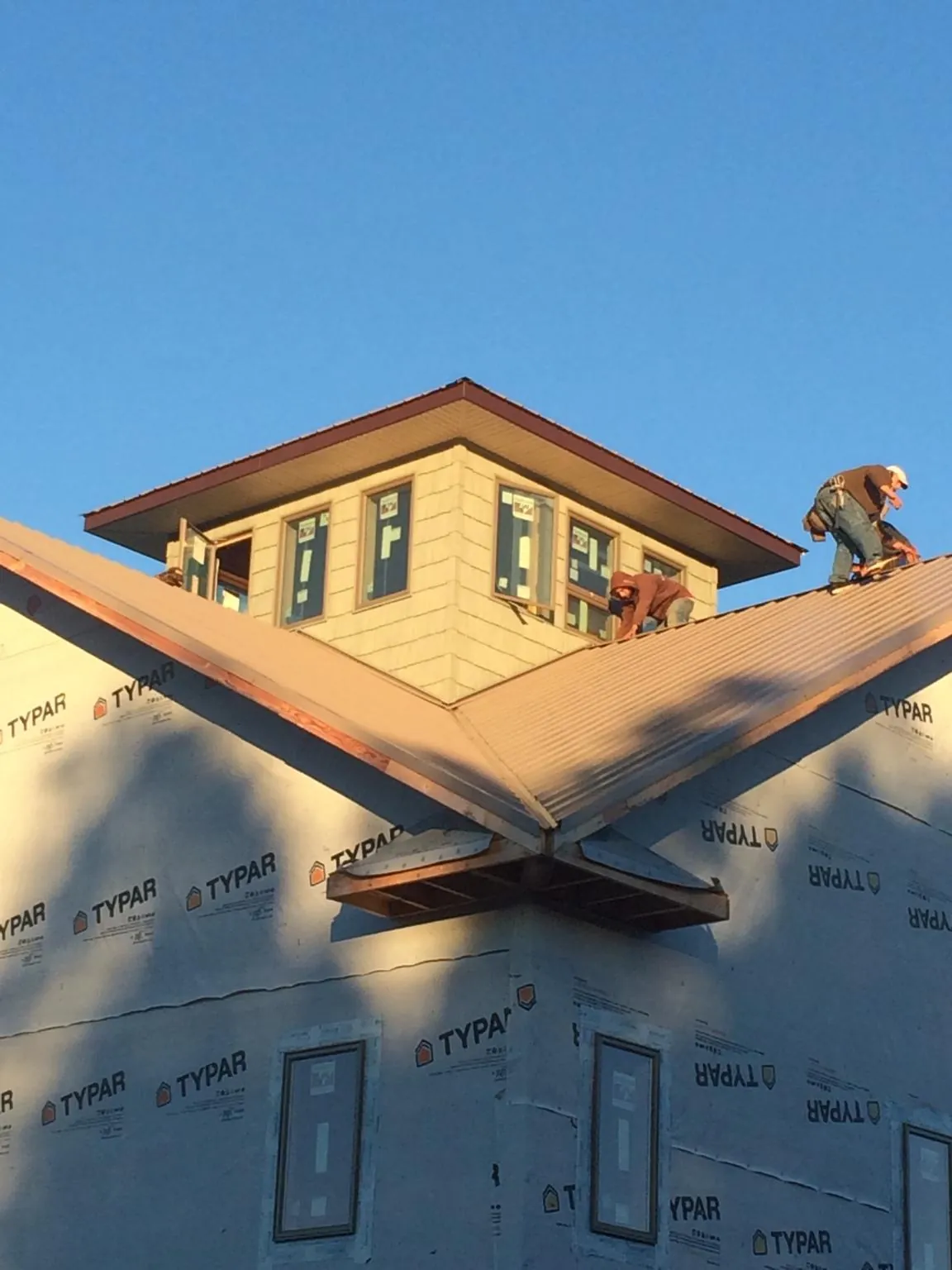 Roofers working around a rooftop cupola on a new metal roof at sunset — Roof Waterproofing in Talmage by Roofing Brothers